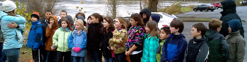 Students gather on the bank of a river during a field trip.